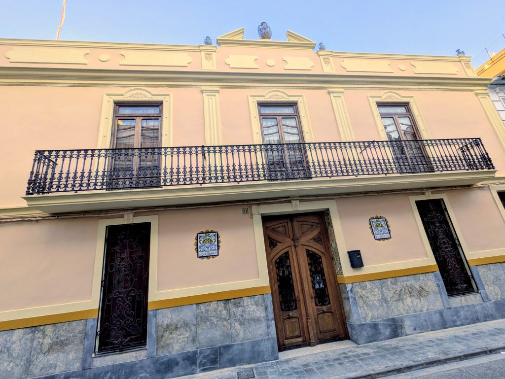 La façade de Casa Mayolica à Manises par une journée ensoleillée, avec des vases en céramique le long de la toiture et un balcon en fer forgé