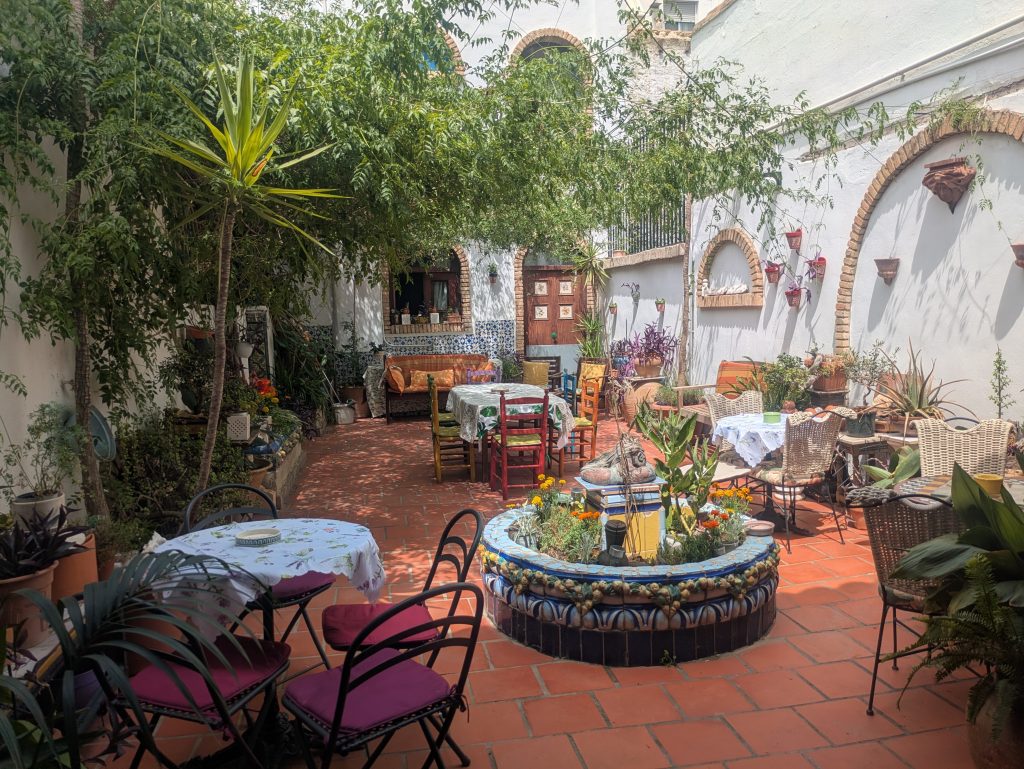The interior patio of Casa Mayolica with a tiled ceramic fountain, dining tables and plants, Manises
